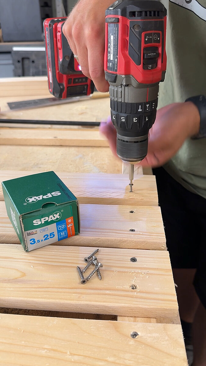 Mobilen Grillwagen bauen Detailaufnahme vom Verschrauben der Holzplanken mit SPAX-Schrauben, präzise Befestigung der Grillwagen-Oberfläche für eine langlebige Konstruktion