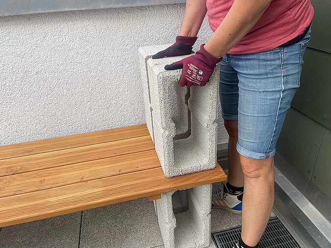 Grillplatz für die Terrasse bauen: Ausrichten eines weiteren Hohlblocks auf der unteren Holzfläche – stabiler Aufbau der zweiten Ebene der DIY-Grillstation für den Außenbereich.