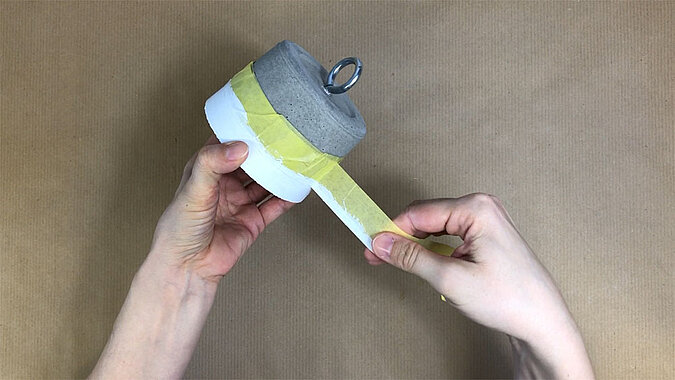 Türstopper aus Beton selber machen – selbst gegossener Beton-Türstopper wird mit Malerkrepp abgeklebt, Vorbereitung für das farbliche Gestalten und Versiegeln der Oberfläche