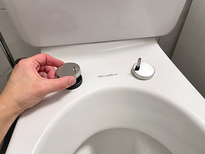Klodeckel wechseln & pflegen – Montage des neuen Toilettensitz-Nahaufnahme, Hand montiert silberne Abdeckkappen