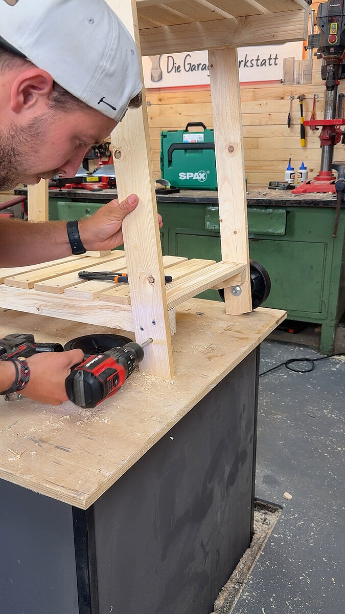 Mobilen Grillwagen bauen beim Montieren der Standfüße und Querstreben aus Holz, Stabilisierung der Konstruktion für einen robusten mobilen Grillwagen