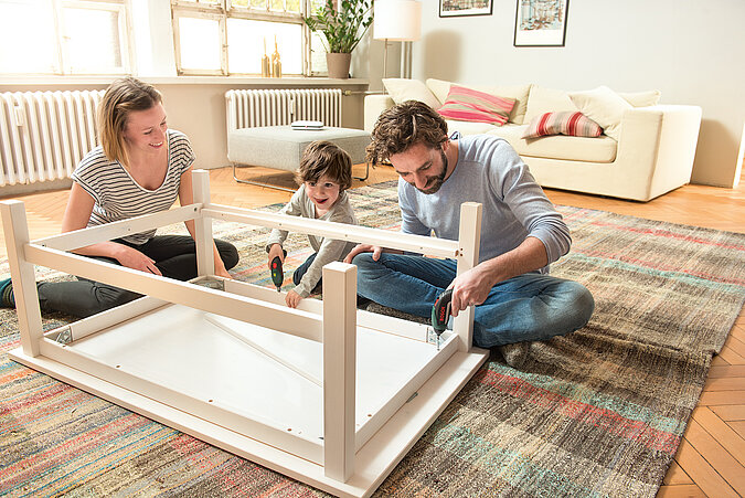 Tipps zum Heimwerken mit Kindern: Eltern bauen mit Sohn gemeinsam einen Esstisch auf