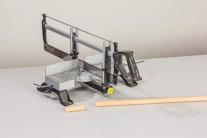 Birkenstamm für einen Raumteiler aus Birkenstämmen wird mit einer Gehrungssäge auf der Werkbank zugeschnitten