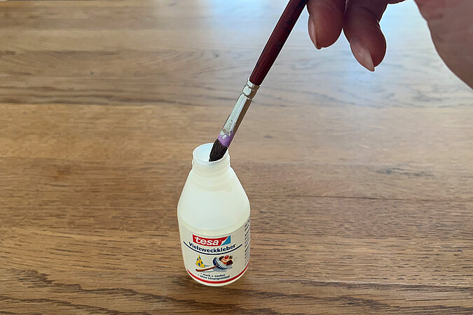 Pinsel taucht in Flüssigkleber