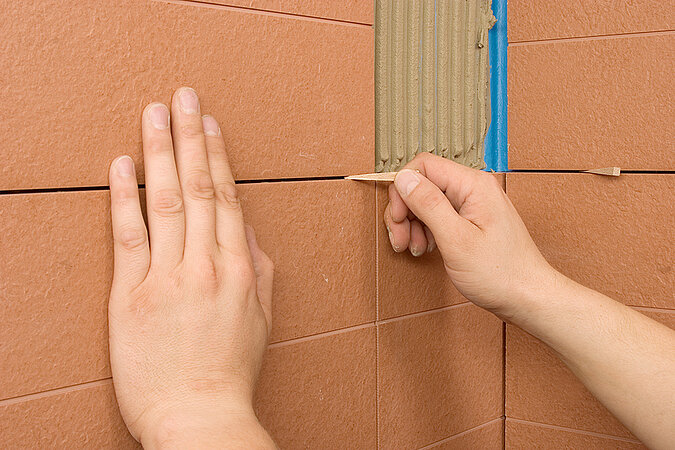 Fliesen an die Wand kleben Ausrichten der Fliesen mit Fugenkreuzen für gleichmäßige Fugenabstände