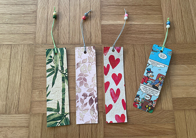 Upcycling aus TetraPak - Lesezeichen mit Serviettentechnic und Comics liegen auf Parkettboden