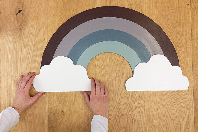 Wandleuchte im Regenbogen-Design bauen – beide weißen Wolken werden an den Enden des farbigen Holz-Regenbogens befestigt.