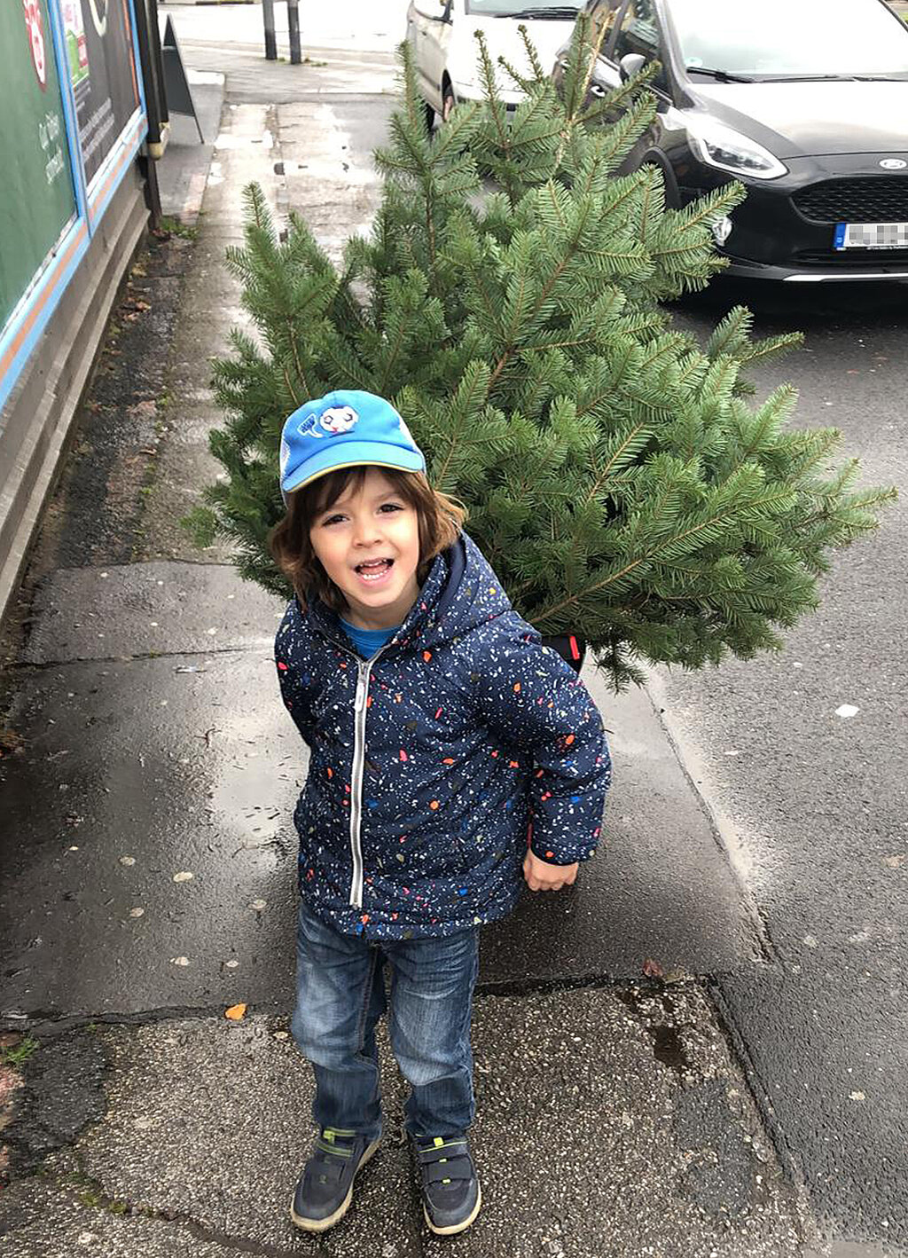 Nachhaltiger Weihnachtsbaum: Tipps für Kauf und Entsorgung – Junge transportiert einen frisch geschlagenen Weihnachtsbaum umweltfreundlich im Bollerwagen nach Hause