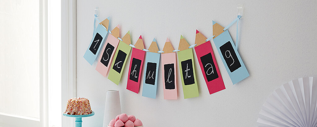 Einschulung Wimpelkette aus buntem Papier als kreative DIY-Deko für die Einschulungsfeier an der Wand aufgehängt