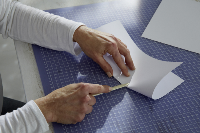 weibliche Haende glaetten Papier mit einem Falzbein