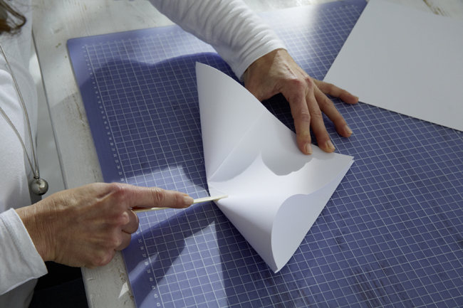 Frau faltet weißes Blatt Papier zum Dreieck 